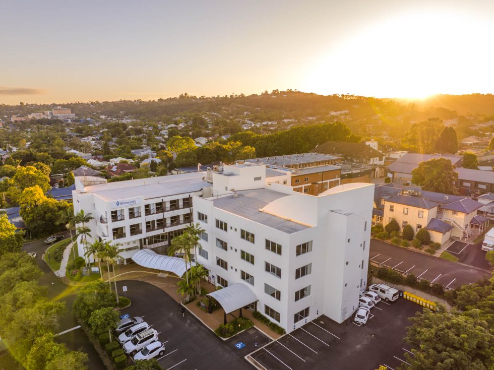 Modern hospital building at sunset with greenery