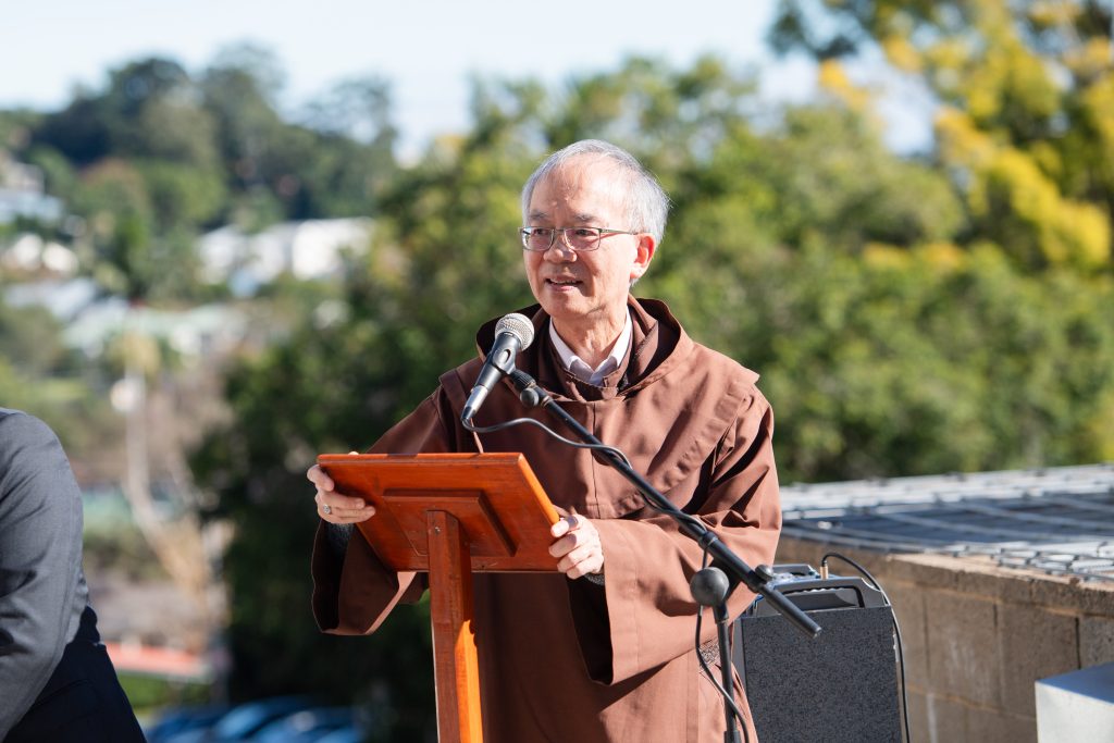 Speaker at outdoor event, brown robe.