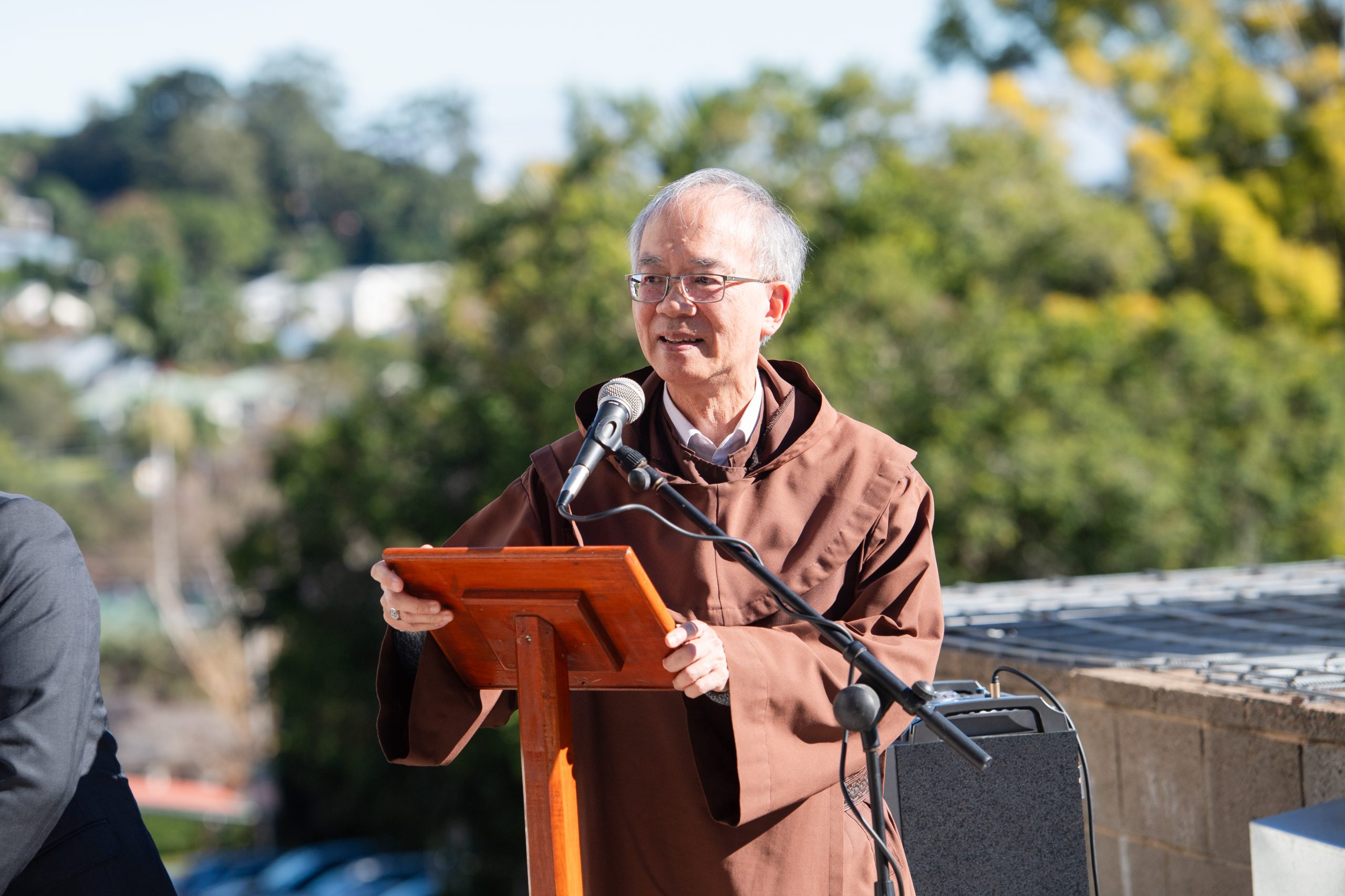Speaker at outdoor event, brown robe.